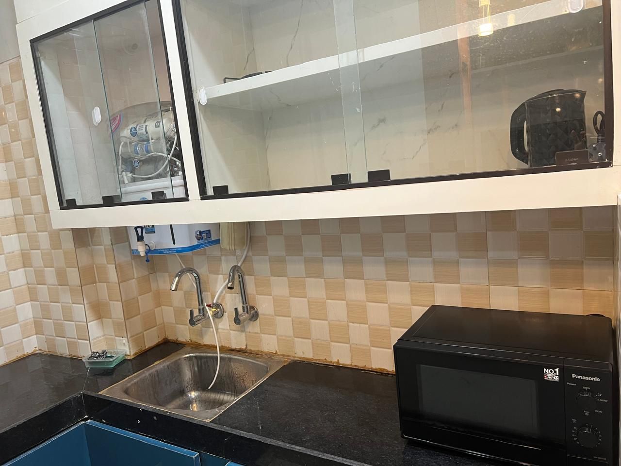 Una cocina con un lavamanos, un microondas y un armario con ventana.
