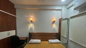 Ein Hotelzimmer mit einem Bett, zwei Wandleuchten, einem Schreibtisch mit Stuhl und einem Kleiderschrank.