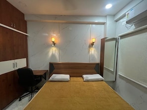 Habitación de hotel con cama, dos lámparas de pared, un escritorio con silla y un armario.