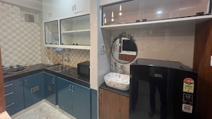 Eine moderne Küche mit blauen Schränken, einem schwarzen Kühlschrank und einer Spüle mit einer dekorativen Schüssel.