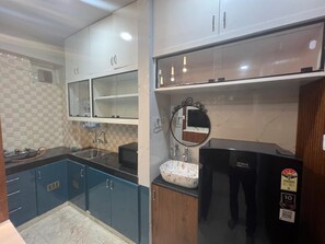 Una cocina moderna con armarios azules, un refrigerador negro y un lavamanos con un cuenco decorativo.