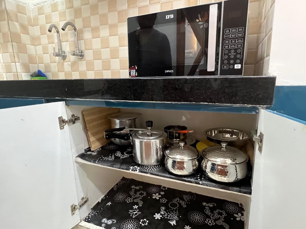 A kitchen with a microwave, a sink, and various cooking utensils.