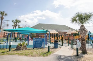 Um parquinho com diversas estruturas de recreação e uma placa indicando o Parque Memorial de Tybee Island.