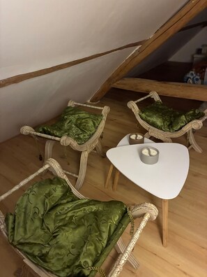 Ein Zimmer mit einem weißen Tisch und zwei Korbstühlen mit grünen Kissen.