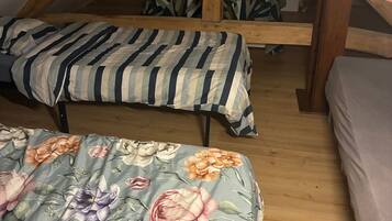 Un dormitorio con dos camas, vigas de madera, una ventana y una mesita de noche.