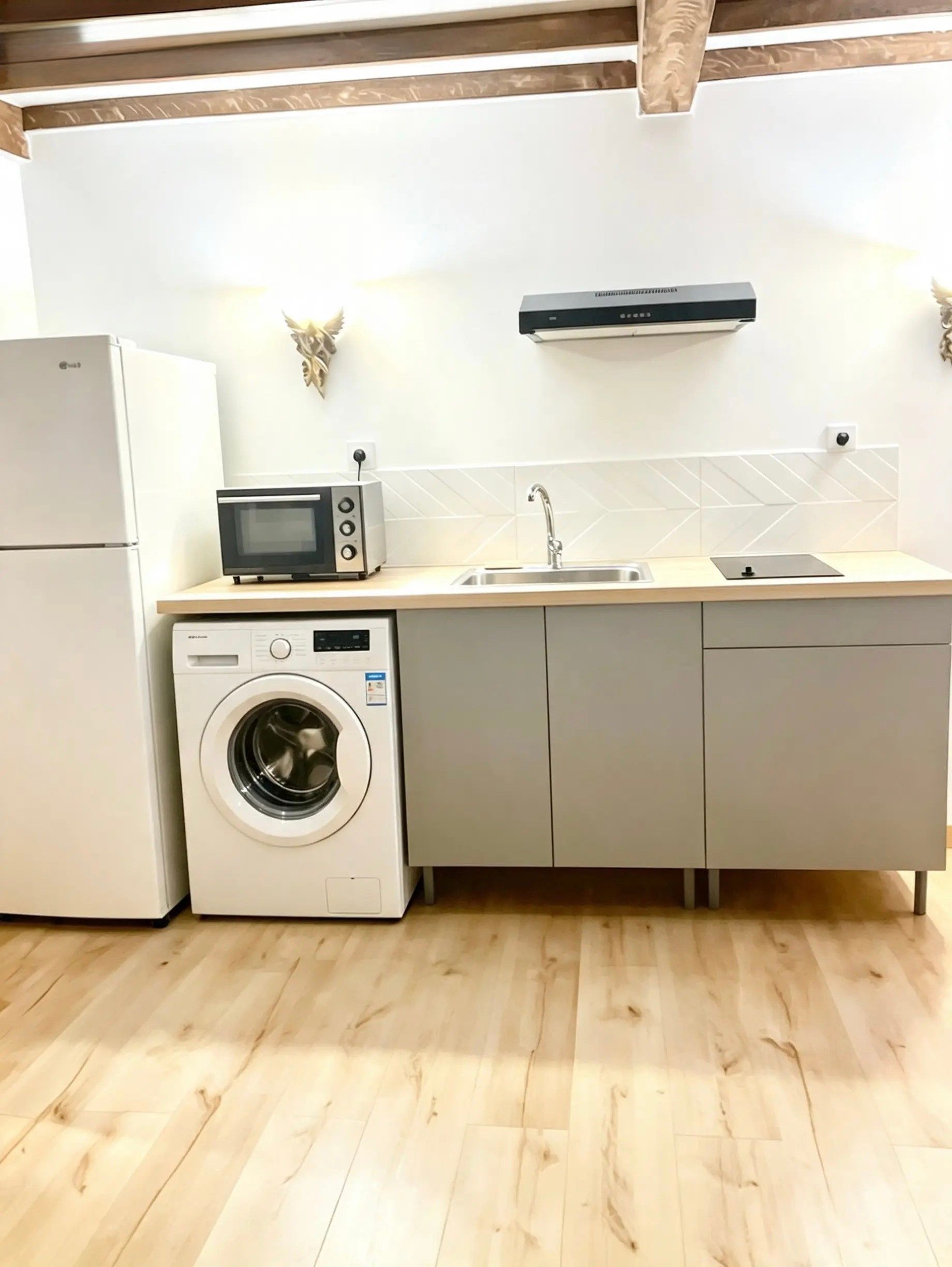 A compact kitchen with a washing machine, microwave, and a sink.