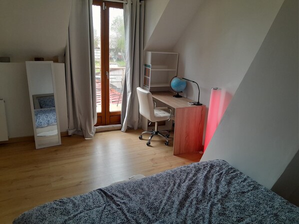 Ein Zimmer mit einem Bett, einem Schreibtisch mit Globus und Lampe sowie einem Ausblick durch ein Fenster.