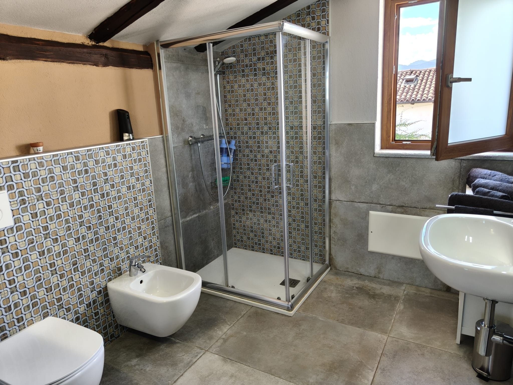 Un bagno con doccia, bidet, lavandino e pareti rivestite di piastrelle.