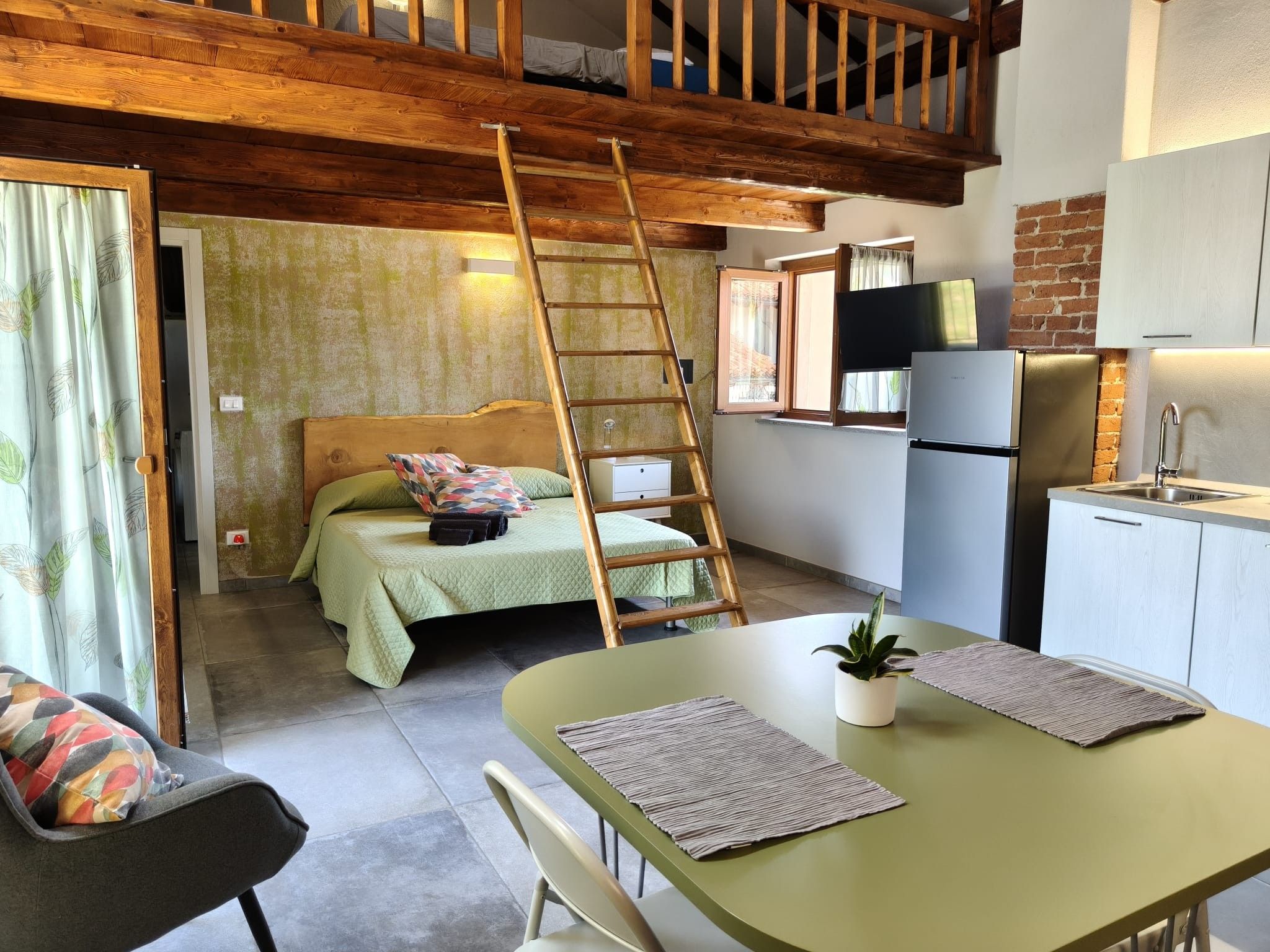 A compact kitchen with a refrigerator, sink, and wooden ceiling.