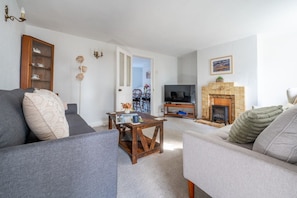 A living room with two sofas, a coffee table, a television, and a fireplace. - Swift Host | Furtherfield | Sleeps 3 | Countryside | Garden (Reedham)