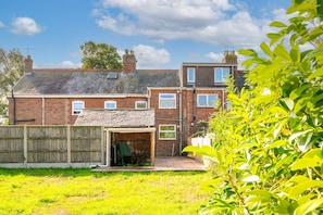 A two-story brick house with a covered patio and a fenced backyard. - Swift Host | Furtherfield | Sleeps 3 | Countryside | Garden (Reedham)