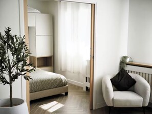 A bedroom with a bed, a chair, a potted plant, and a wardrobe. - Apartment Suite in Cagnes-sur-Mer (Cagnes-sur-Mer)