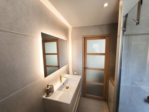 A modern bathroom with a white sink, a mirror, and a glass shower door. - Apartment Suite in Cagnes-sur-Mer (Cagnes-sur-Mer)