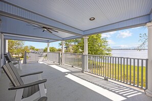 A covered outdoor area with a view of a body of water, a seating area with benches, and a railing. - Downtown Riverfront Retreat (New Bern)