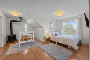 A bedroom with a bed, a desk, a chair, a radiator, and a window. - Downtown Riverfront Retreat (New Bern)