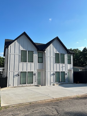 A two-story building with a symmetrical facade, green shutters, and a clear sky. - Modern, beautifully furnished 3-bedroom condo near Downtown Greenville, SC (Greenville)