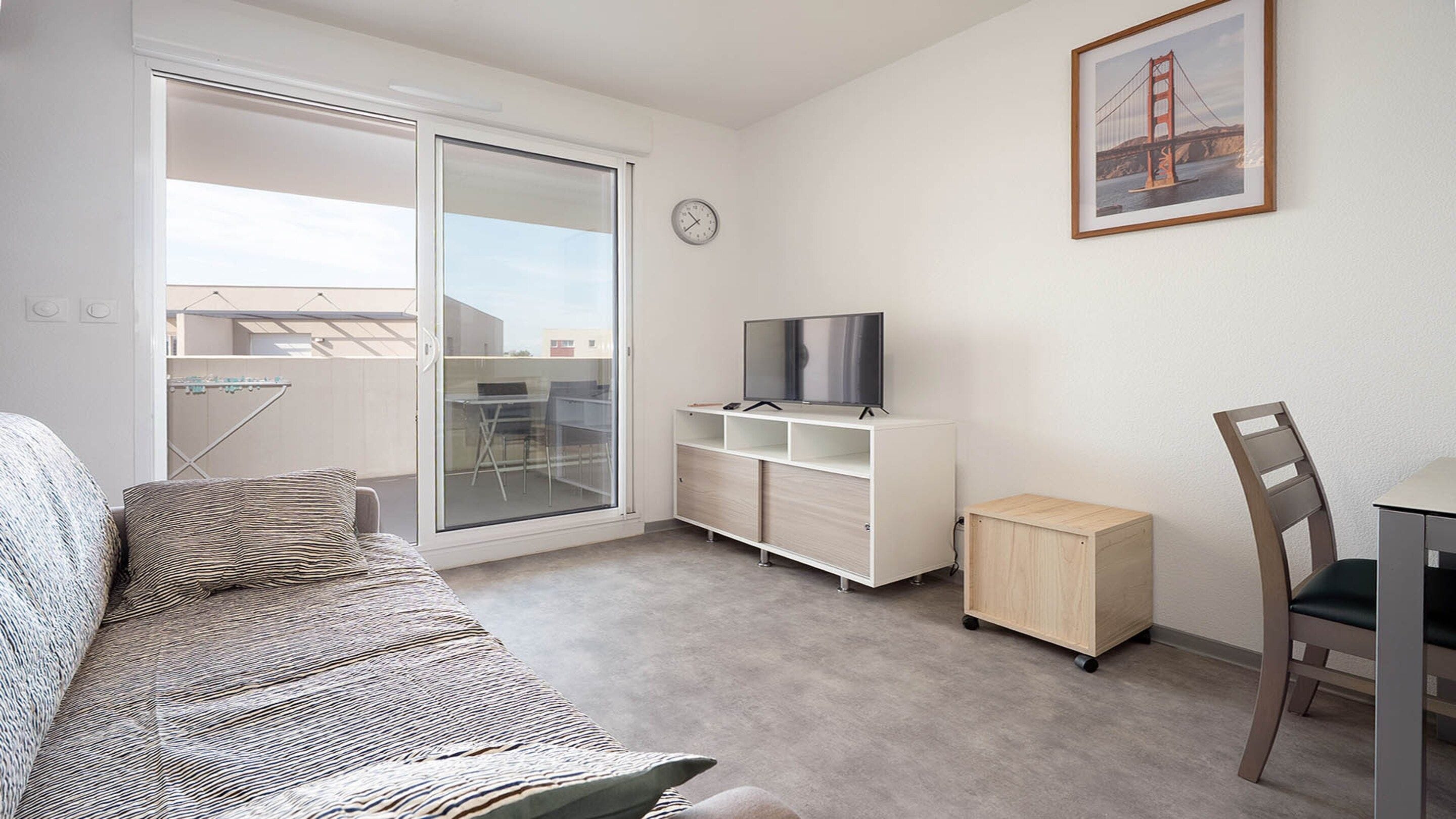A modern living room with a sofa, a television on a stand, a small cabinet, and a chair.