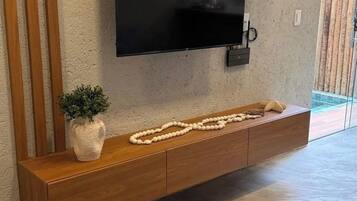 Un soggiorno moderno con una TV a schermo piatto montata su una consolle in legno, una pianta in vaso e una ghirlanda decorativa di perline.