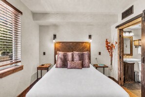 A bedroom with a large bed, bedside tables, a nightstand, a window with blinds, a mirror, and a view of the outdoors. - Silverado Lodge 129 | Canyons Views | Pool | Hot Tub | Near Lifts (Park City)