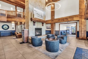 A spacious lobby with a stone fireplace, seating area, and a view of the upper level. - Silverado Lodge 129 | Canyons Views | Pool | Hot Tub | Near Lifts (Park City)