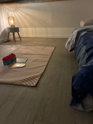 A bedroom with a bed, a bedside table, a lamp, and a rug.