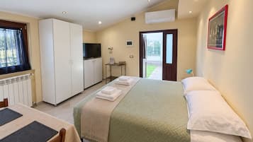 Habitación de hotel con cama, escritorio, televisión y ventana con cortinas.