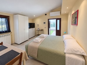 A hotel room with a bed, a desk, a television, and a window with curtains.