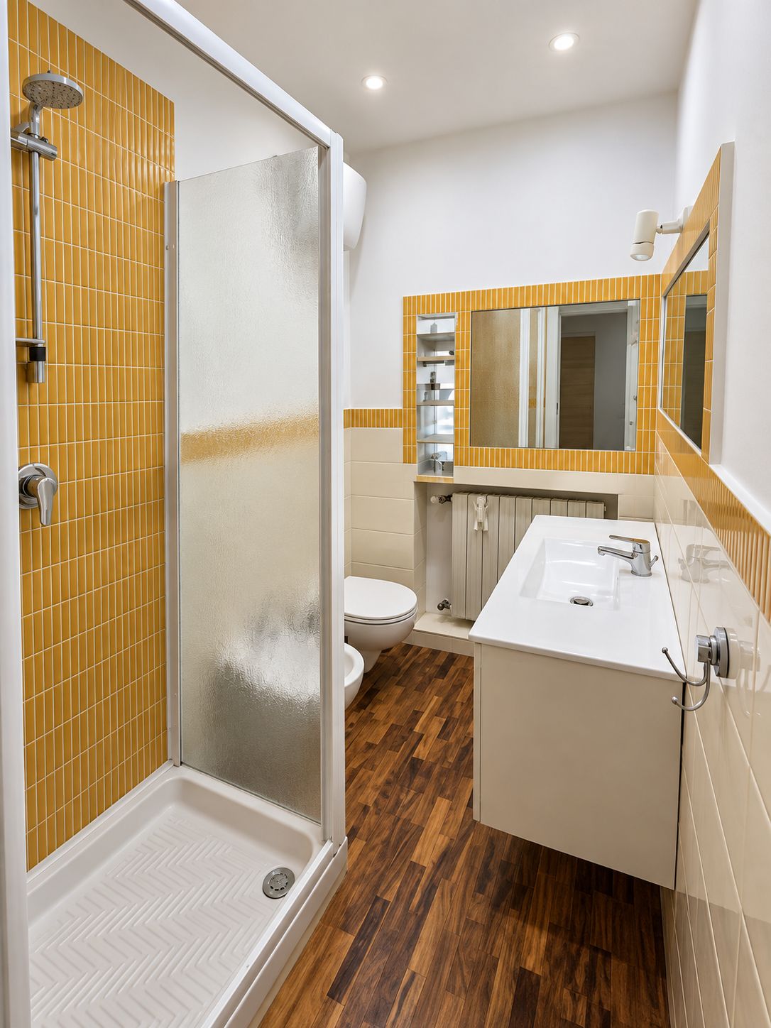 A modern bathroom with a glass-enclosed shower, a white sink, and a toilet.