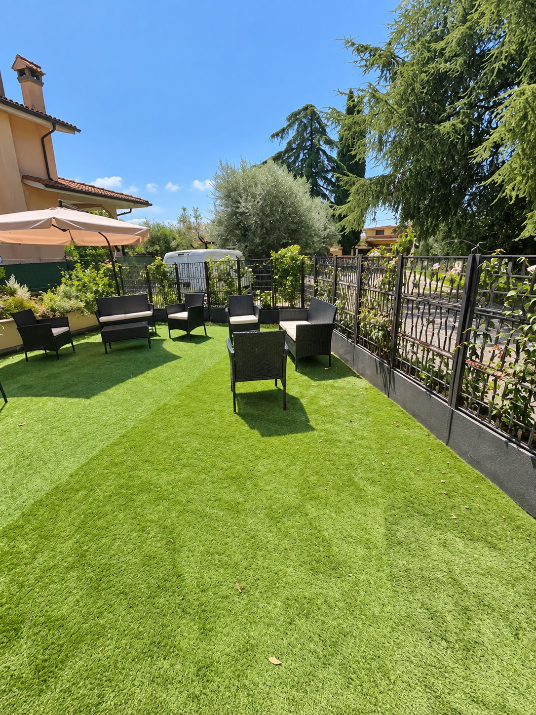 A patio with artificial grass, outdoor furniture, and a metal fence.
