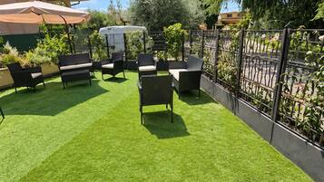 A patio with artificial grass, outdoor furniture, and a metal fence.