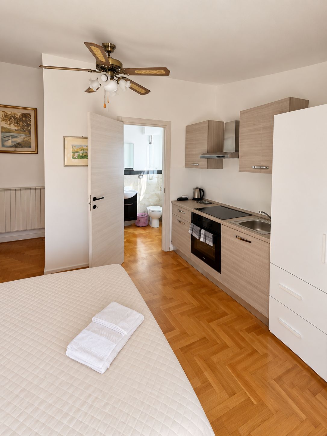 Une chambre à coucher moderne avec un lit, un ventilateur de plafond et une vue sur la salle de bain.