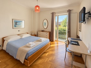 Une chambre à coucher comprenant un lit, une table de chevet, une lampe, un téléviseur et une vue sur l’extérieur.