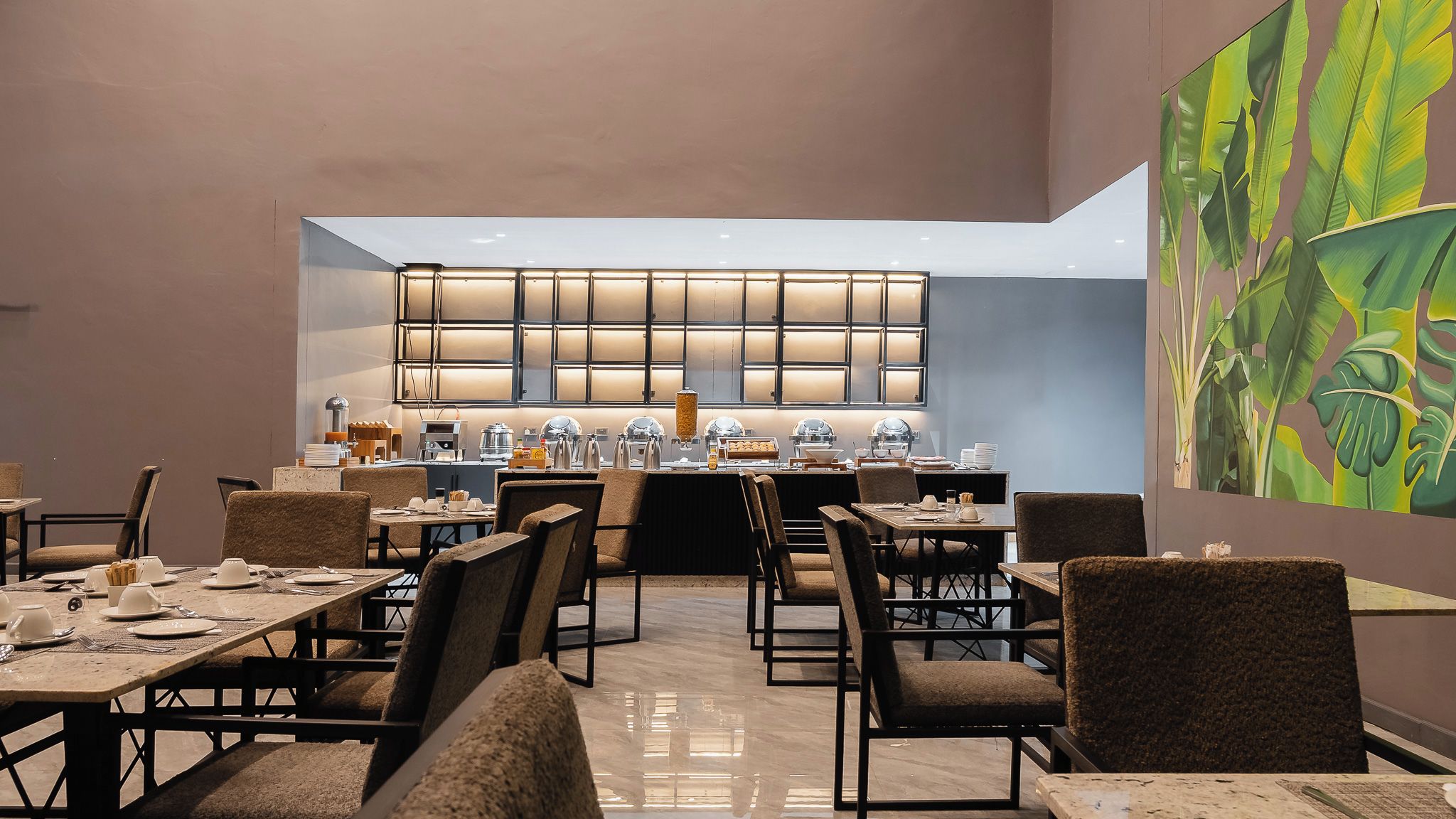 A modern dining area with multiple tables and chairs, a buffet counter with various food items, and a large window with a grid pattern.