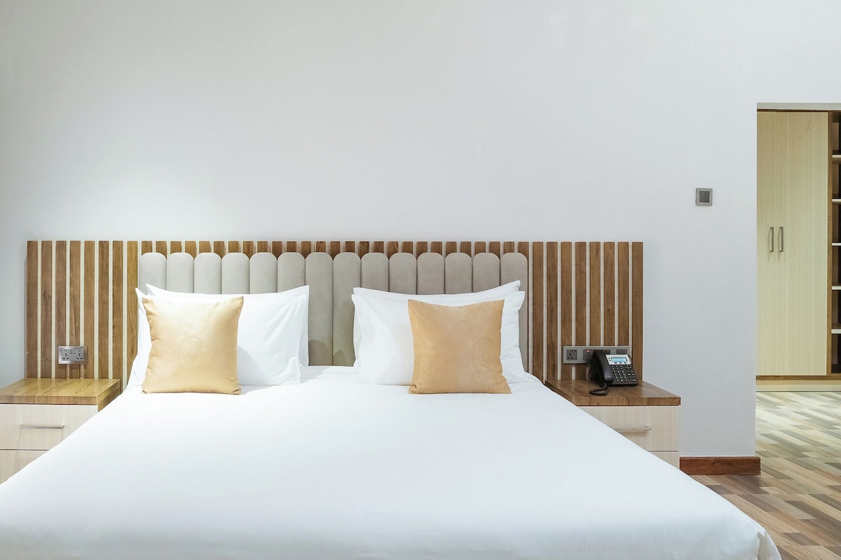 A hotel room with a large bed, two bedside tables, a telephone, and a wooden wardrobe.