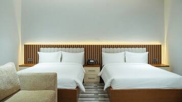 A hotel room with two beds, a wooden headboard, bedside tables, a phone, and a chair.