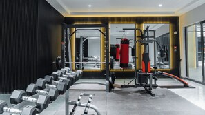 Ginásio com equipamento de musculação, um saco de pancadas e um espelho refletindo o interior.