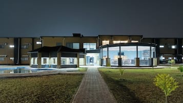 Um hotel com piscina, área de estar coberta ao ar livre e um caminho pavimentado.