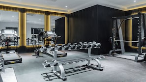 A modern gym with various exercise equipment, including dumbbells, a bench press, and a squat rack. - The Urban Stay Kalumbila (Kalumbila)