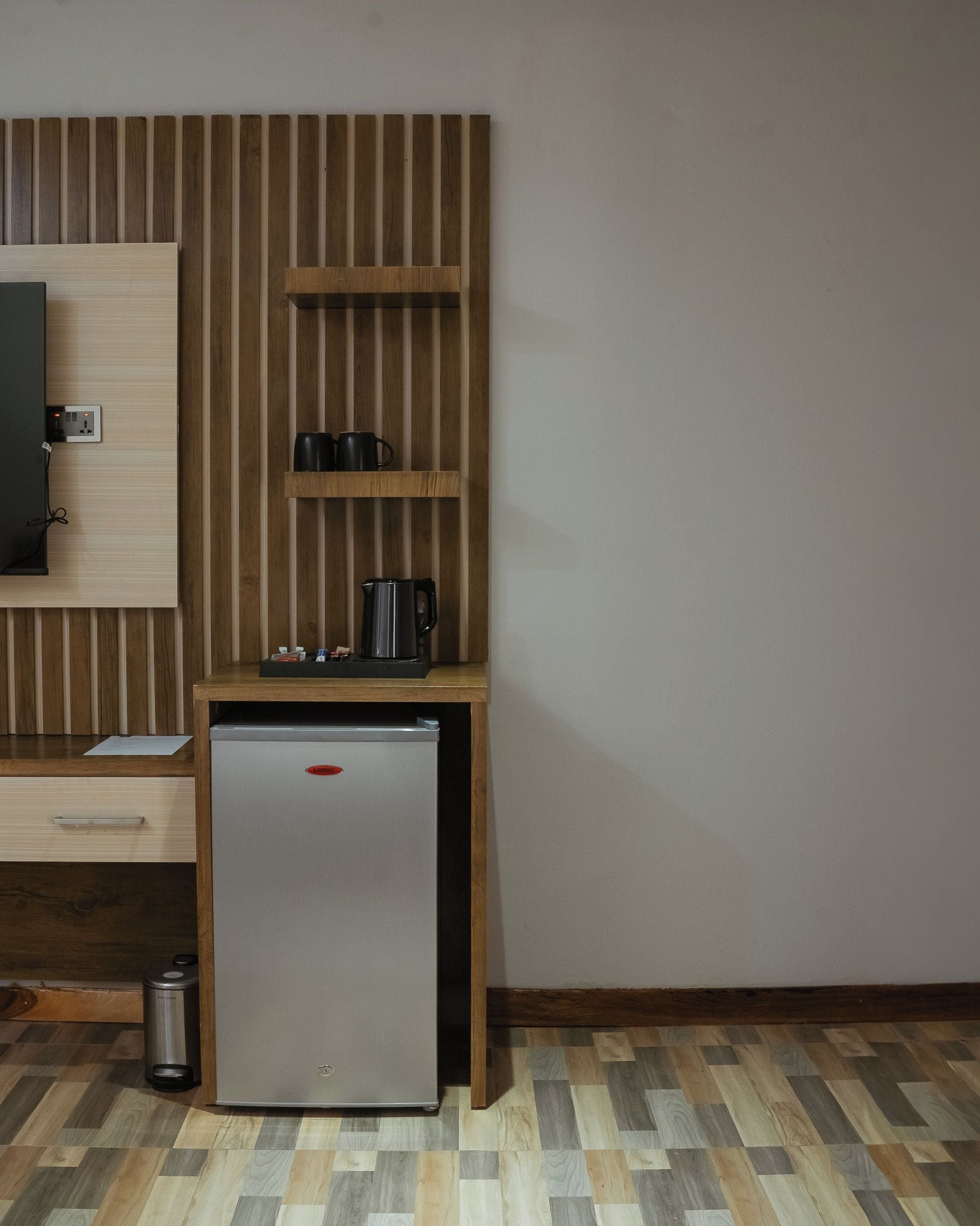 A compact kitchenette with a refrigerator, a small countertop, and a wooden panel wall.