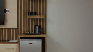 A compact kitchenette with a refrigerator, a small countertop, and a wooden panel wall.