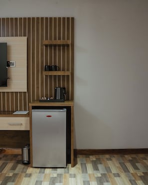 Uma cozinha compacta com geladeira, bancada pequena e parede revestida em madeira.