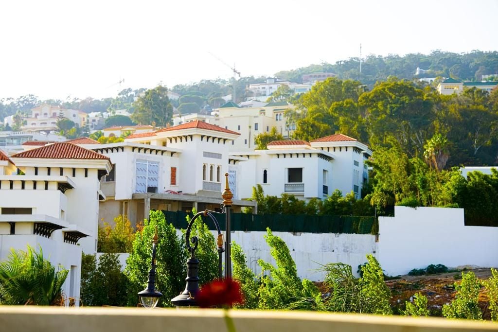 A residential area with white buildings, red-tiled roofs, and lush greenery.