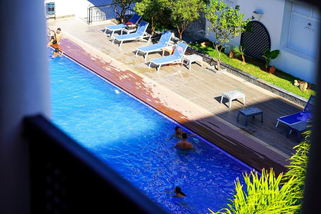 Una piscina con sillas de descanso y una mesita, rodeada de follaje.