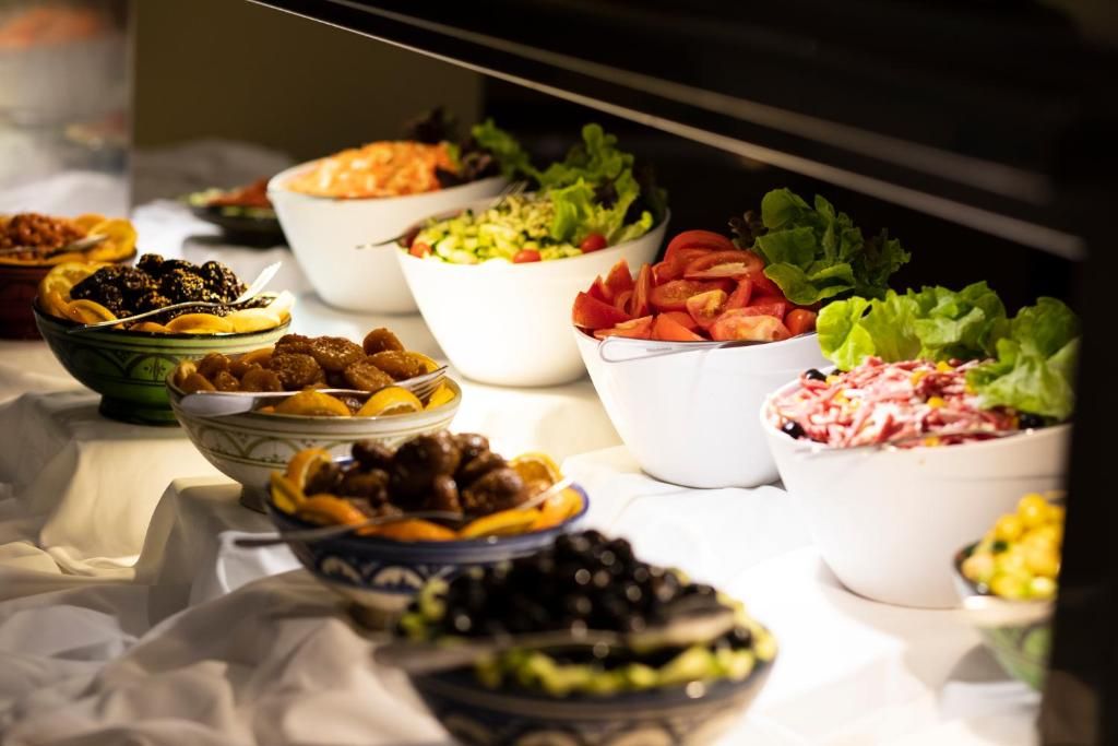 A buffet table with various dishes including salads, meats, and fruits.