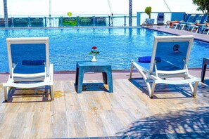 A poolside area with lounge chairs and a small table with a vase.