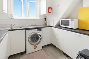 A compact kitchen with a washing machine, a microwave, and a sink.