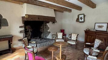 Un intérieur rustique agrémenté d’une cheminée en pierre, de poutres en bois et de meubles traditionnels.