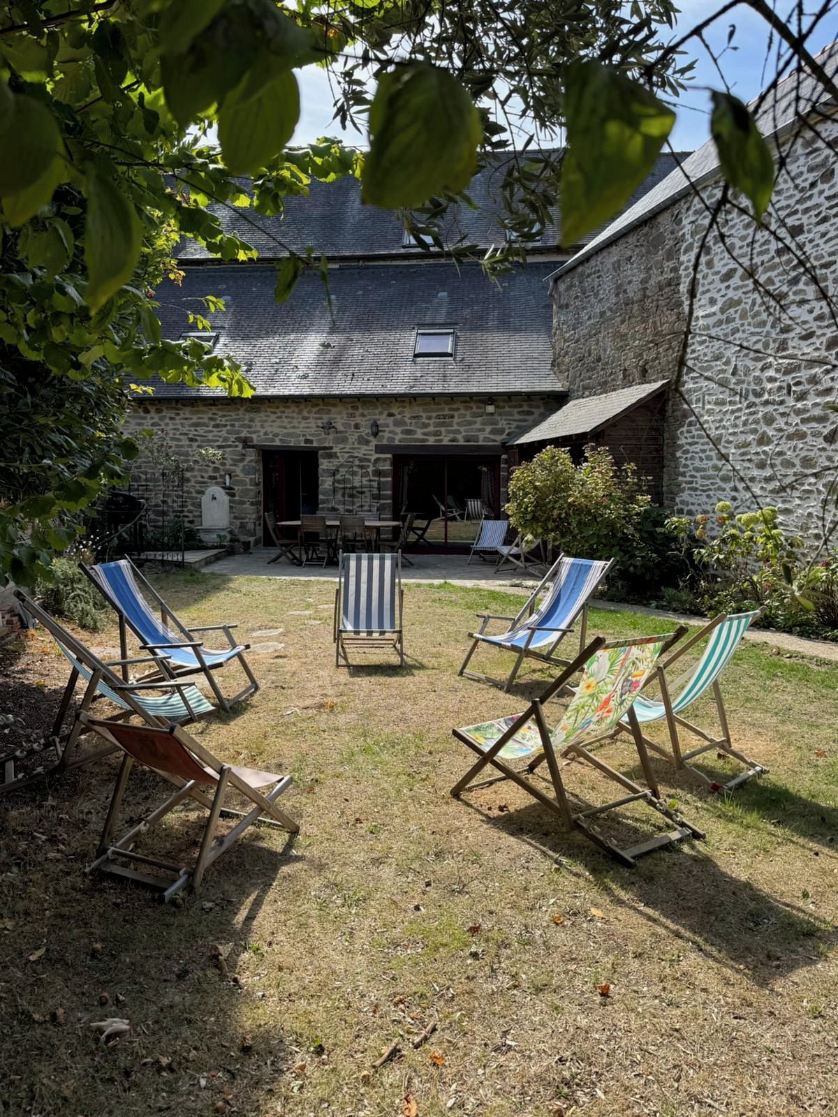 Un bâtiment en pierre doté d’un patio couvert avec des espaces de détente en plein air.