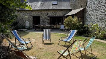 Un bâtiment en pierre doté d’un patio couvert avec des espaces de détente en plein air.