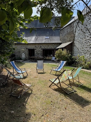 A stone building with a covered patio area featuring outdoor seating.